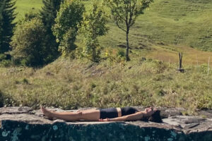 Ein Frau liegt inmitten schöner Natur ganz entspannt auf dem Rücken. Dies ist Yoga Nidra, die Tiefenentspannung.