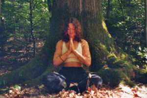 Junge Frau in Yogahaltung vor Baum